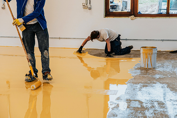 Worker, coating floor with self leveling epoxy resin in industri